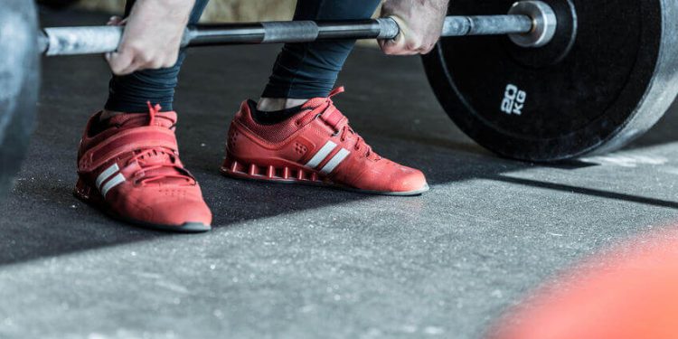 powerlifter si allena con bilanciere con scarpe adidas rosse